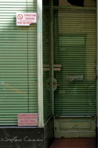 Porta di un negozio con serrande chiuse e avvisi di chiusura in italiano