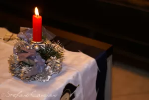 Centrotavola festivo con candela Candela rossa su un centrotavola natalizio con pigne e decorazioni in blu