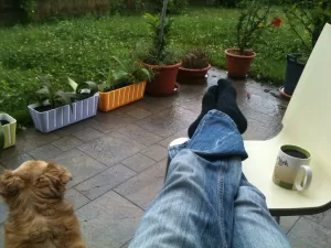 Momento di Relax in Giardino Persona rilassata con caffè e cane in giardino, circondata da piante