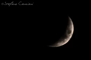 Luna crescente con dettagli visibili sulla sua superficie in un cielo notturno