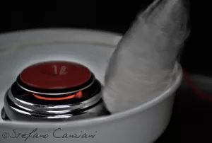 Una macchina per zucchero filato con una ciotola bianca e un cerchio rosso che produce zucchero filato