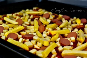 Pizza con patatine e wurstel Pizza con patatine e wurstel tagliati a pezzi su una teglia