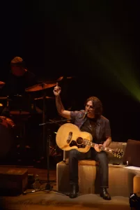 Luciano Ligabue – Concerto di musica dal vivo Luciano Ligabue - Musicista in scena con chitarra acustica, suonando durante un concerto dal vivo