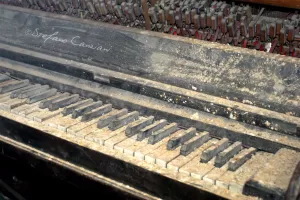Una tastiera di pianoforte coperta di polvere in un ambiente abbandonato