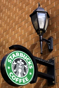 Insegna del caffè Starbucks Insegna di Starbucks con lampione in un'estetica urbana su muro di mattoni