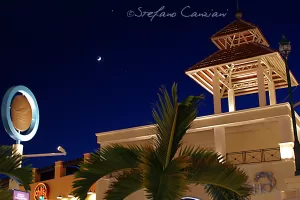 Veduta notturna di un edificio con una torre e una mezza luna nel cielo blu profondo