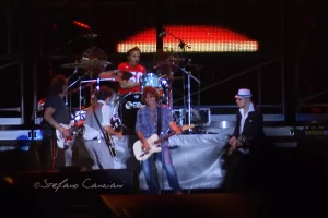 Luciano Ligabue – Concerto della Band Luciano Ligabue - Band musicale in concerto con chitarristi e un batterista su un palco illuminato