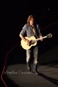 Luciano Ligabue – Concerto del chitarrista Luciano Ligabue - Chitarrista in concerto che suona una chitarra acustica su un palco scuro