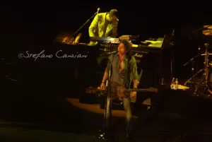 Luciano Ligabue – Concerto dal vivo di un artista musicale Luciano Ligabue - Un musicista che suona la chitarra sul palco mentre un'altra persona suona la tastiera