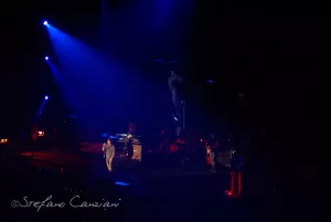 Luciano Ligabue - Concerto dal Vivo Luciano Ligabue - Concerto dal vivo con artisti sul palco illuminato da luci blu e arancioni