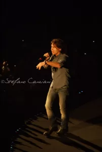 Luciano Ligabue - Concerto del Cantante Luciano Ligabue - Cantante in concerto sul palco con abbigliamento informale e microfono in mano