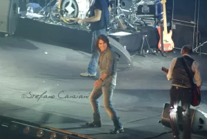 Luciano Ligabue - Concerto dal vivo con artista sul palco Luciano Ligabue - Un cantante sul palco durante un concerto live con strumenti musicali sullo sfondo