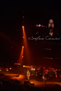 Luciano Ligabue - Concerto dal vivo emozionante Luciano Ligabue - Concerto dal vivo con sul palco musicisti e un artista principale sotto un grande schermo