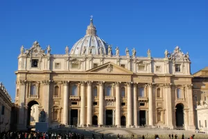 Facciata della Basilica di San Pietro con cielo blu e visitatori in primo piano