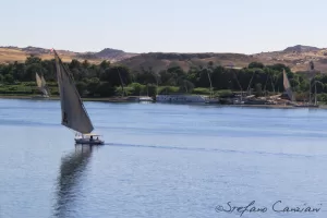 Una feluca che naviga sul fiume Nilo circondata da colline verdi
