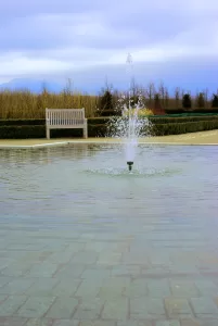 Fontana al centro di un'area verde con panchina in un parco tranquillo