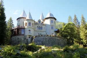 Castello elegante con torri di pietra circondato da alberi e vegetazione