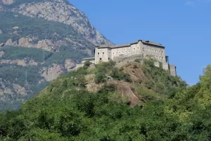 Fortezza su una collina verde circondata da montagne in Valle d'Aosta