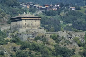 Castello antico situato su una collina circondato da vegetazione e abitazioni in lontananza
