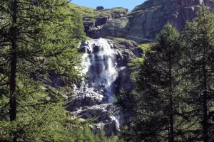 Cascata circondata da alberi verdi in un paesaggio montano