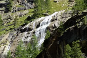 Cascata che scorre su una roccia circondata da alberi in un paesaggio montano