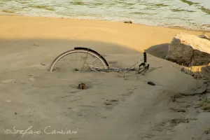 Bici arrugginita abbandonata sulla sabbia di una spiaggia