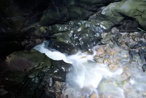 Un fiume che scorre tra rocce scure e ciottoli bagnati in un ambiente naturale