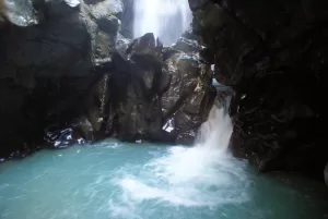 Cascata che scorre tra rocce con acqua turchese in una grotta naturale