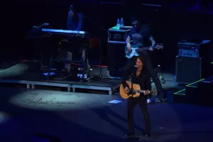 Luciano Ligabue - Concerto di Chitarra dal Vivo Luciano Ligabue - Un cantante con chitarra sul palco durante un concerto, con musicisti di supporto sullo sfondo