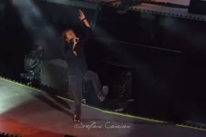 Luciano Ligabue - Concerto dal Vivo Luciano Ligabue - Cantante sul palco durante un concerto dal vivo con luci brillanti e atmosfera coinvolgente