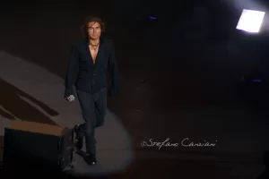 Luciano Ligabue - Prestazione dal vivo di un artista Luciano Ligabue - Un artista che si esibisce sul palco con una chitarra, illuminato da un riflettore