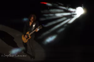 Luciano Ligabue - Chitarrista in concerto Luciano Ligabue - Chitarrista su palco illuminato, con raggi di luce che colpiscono durante un concerto dal vivo