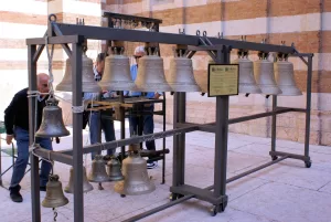 Campane di bronzo in esposizione in un'installazione artistica con persone che osservano