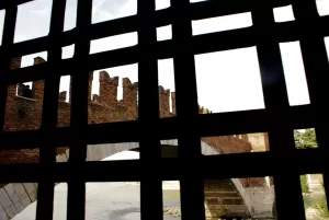 Vista di un antico castello attraverso una grata con muri di mattoni