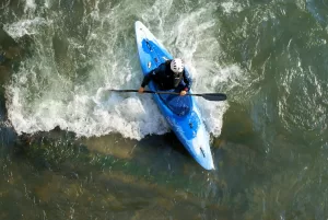 Un uomo che fa kayak in un fiume, circondato da acque mosse