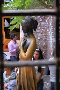 Statua di donna in piazza Statua dorata di donna in una piazza affollata con visitatori e vegetazione