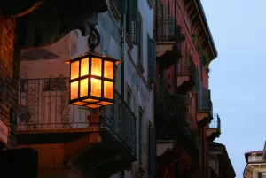 Lanterna vintage illuminata appesa a un balcone in una strada cittadina al tramonto