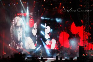 Luciano Ligabue - Concerto dal Vivo Luciano Ligabue - Artista sul palco con schermo grande che mostra la sua immagine durante concerto dal vivo