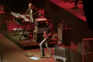 Luciano Ligabue - Concerto dal Vivo di Musicisti Luciano Ligabue - Musicisti che suonano dal vivo, tastiera e chitarra in un concerto con luci rosse