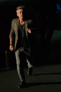 Luciano Ligabue - Uomo elegante in movimento Luciano Ligabue - Uomo che cammina con un abito elegante in un ambiente poco illuminato