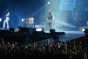 Luciano Ligabue - Concerto dal vivo con artisti in primo piano Luciano Ligabue - Un concerto dal vivo con artisti che si esibiscono su un palco illuminato e una folla entusiasta