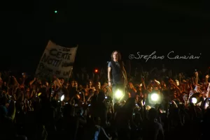 Luciano Ligabue - Artista in concerto tra il pubblico Luciano Ligabue - Concert live di un artista circondato da fan con cartelli e luci accese