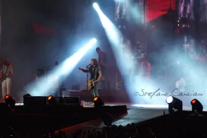 Luciano Ligabue - Concerto dal Vivo Luciano Ligabue - Un musicista sul palco durante un concerto, illuminato da luci intense con il pubblico in vista