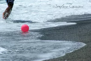 Un tocco di colore sul bagnasciuga Un pallone rosa che galleggia sulla spiaggia con onde che si infrangono