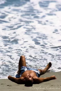 Un tuffo tra sé stessi e la natura Uomo sdraiato sulla spiaggia con le onde del mare che si infrangono