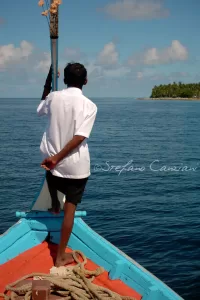 Lo sguardo si perde dove finisce il mare Uomo in barca a remi con vista su un'isola tropicale nel mare cristallino