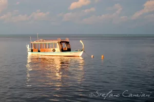 Barca tradizionale galleggiante sull'acqua calma al tramonto