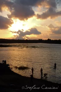 Tramonto sul fiume con silhouette di persone e nuvole colorate