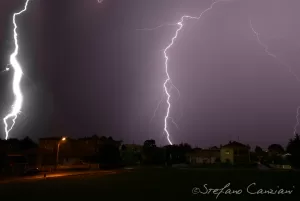 Tempesta Elettrica Notturna Fulmini nel cielo notturno sopra un paesaggio urbano, creando un effetto drammatico e mozzafiato